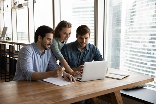 three people in front of a laptop