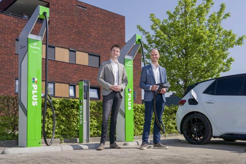 two men standing in front of ev chargers